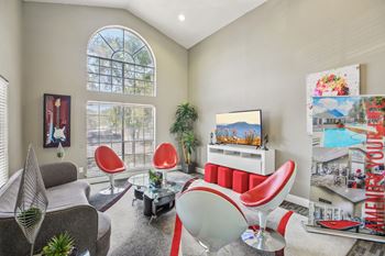 A living room with a grey sofa, red chairs, and a TV.